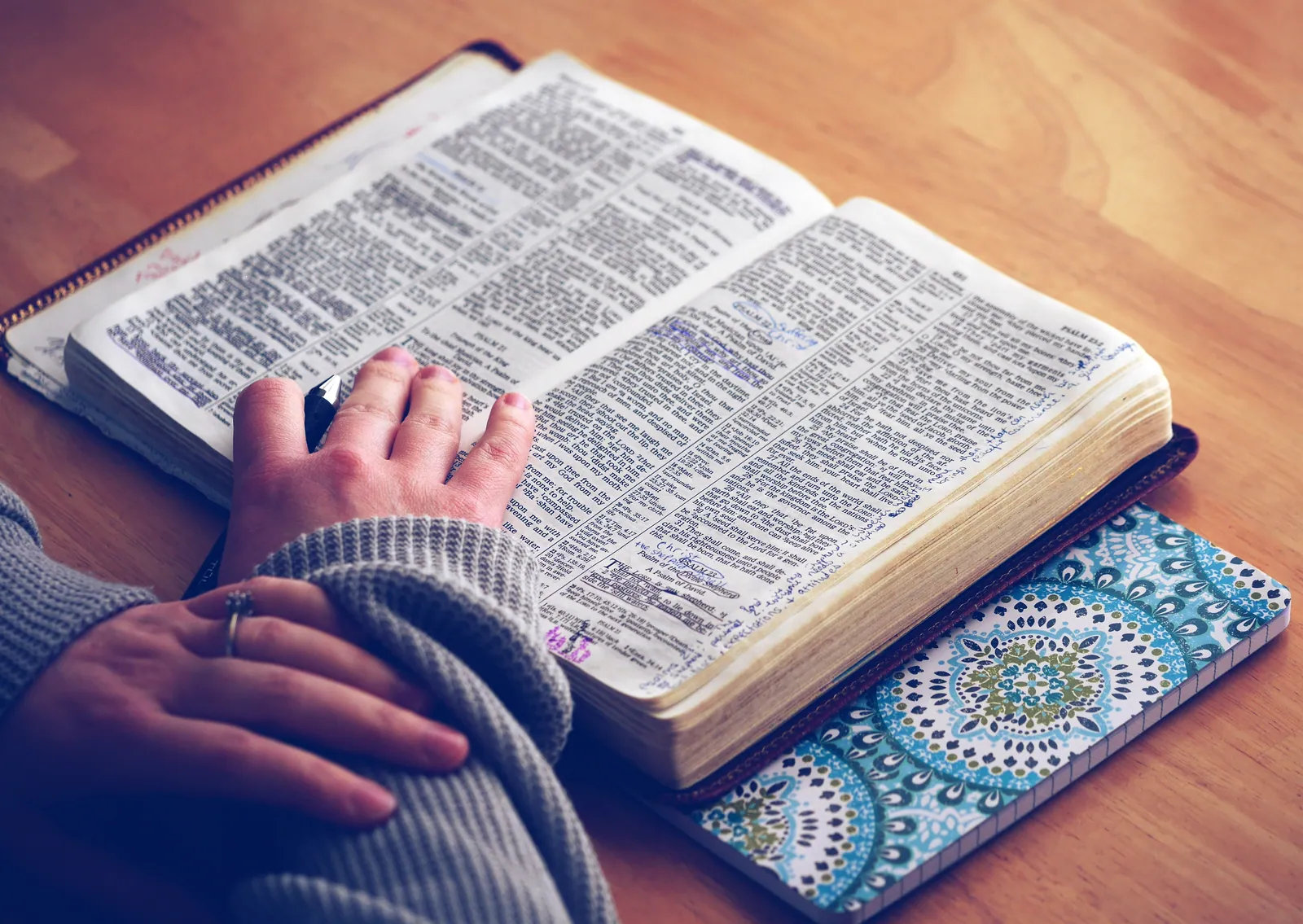 A person studying and taking notes in an open Bible, representing love for God through thoughtful Scripture study