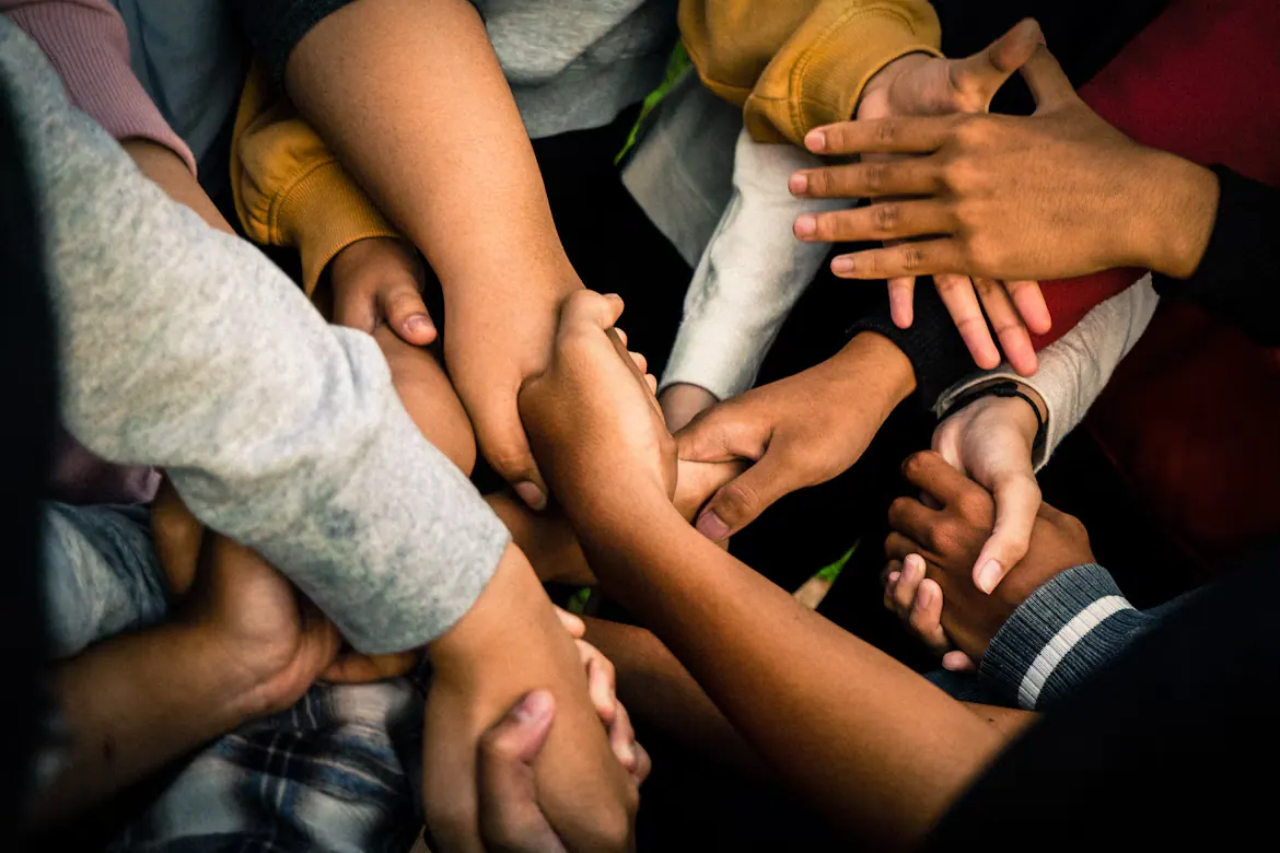 Diverse group joins hands together to express unity, care, and love for one another