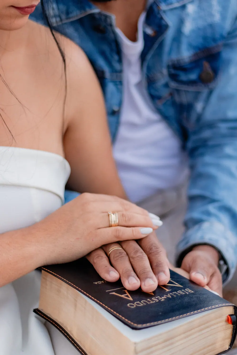 Couple rests joined hands on a Bible as a sign of faith and commitment