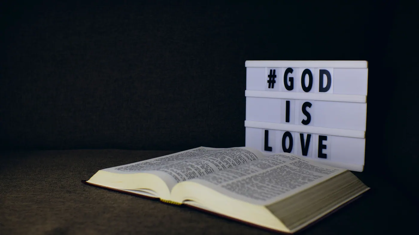 Open Bible beside a lightbox reading God is Love