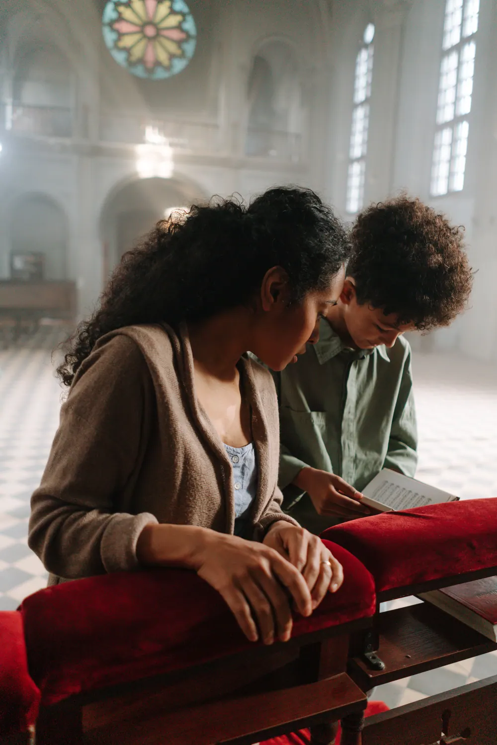 Mother and son read and pray with a Bible inside a church